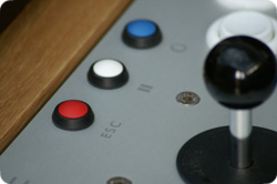 Close-up of arcade joystick and buttons on silver control panel